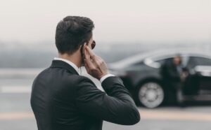 Mann im Personenschutz blickt auf Fahrzeug mit Schutzperson